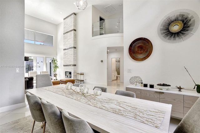 tiled dining area featuring a fireplace, brick wall, and a high ceiling