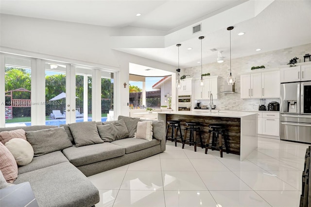 tiled living room featuring high vaulted ceiling and french doors