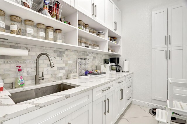 bar featuring light tile patterned floors, decorative backsplash, white cabinets, and light stone countertops