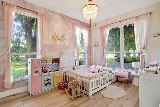 bedroom with a crib and light hardwood / wood-style floors