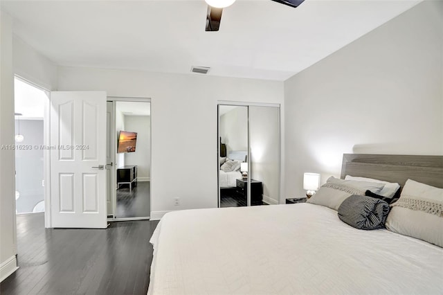 bedroom with ceiling fan, dark wood-type flooring, and two closets