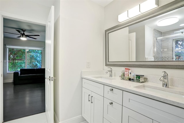 bathroom with double vanity, a shower with shower door, and ceiling fan