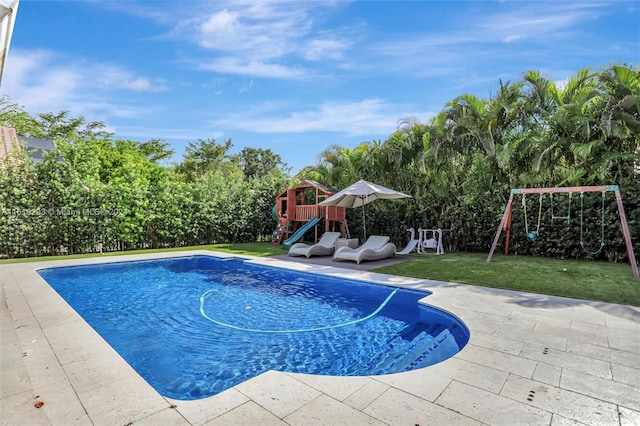 view of swimming pool featuring a playground and a lawn