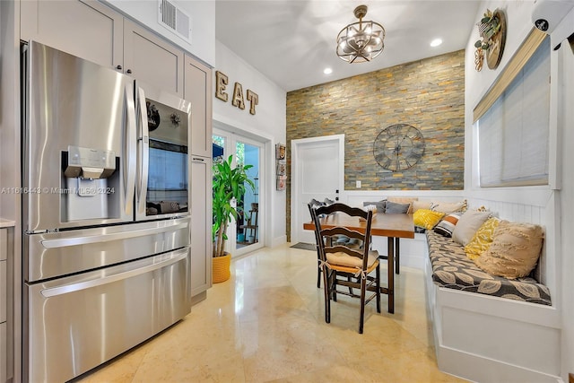 kitchen featuring gray cabinetry, stainless steel fridge, breakfast area, and a notable chandelier