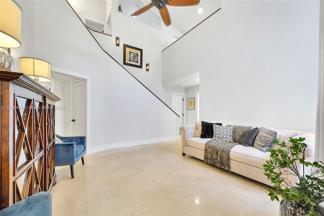 living room with ceiling fan and a towering ceiling