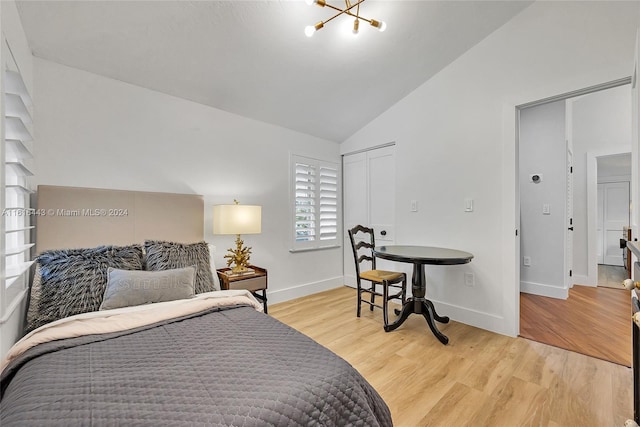 bedroom with a closet, light hardwood / wood-style flooring, vaulted ceiling, and an inviting chandelier