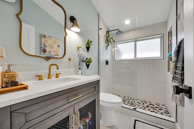 bathroom with tile patterned flooring, a tile shower, vanity, and toilet