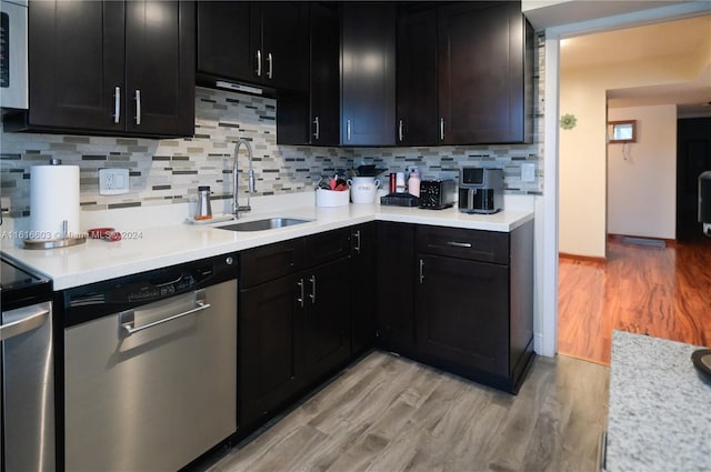 kitchen featuring light hardwood / wood-style floors, stainless steel dishwasher, tasteful backsplash, and sink