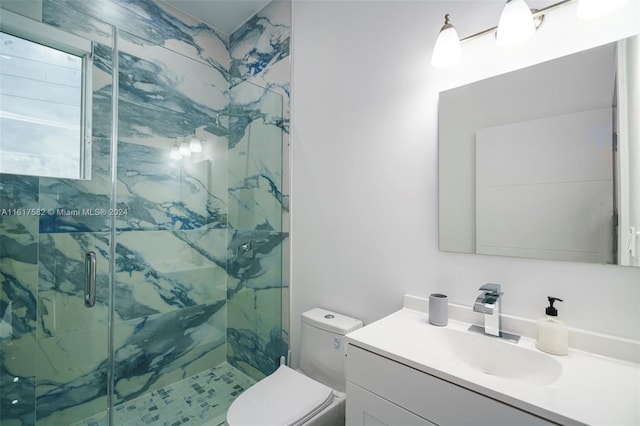 bathroom featuring a shower with shower door, toilet, and vanity