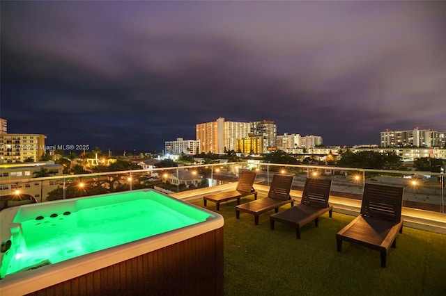 patio at night featuring a jacuzzi