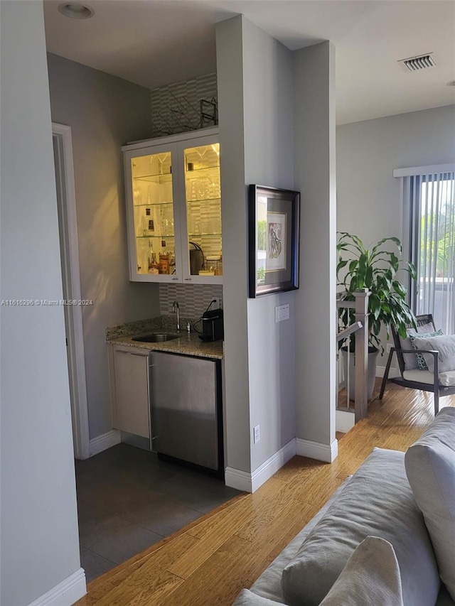 bar with wood finished floors, a sink, visible vents, baseboards, and indoor wet bar