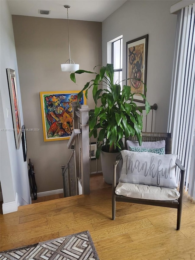 living area with baseboards, visible vents, wood finished floors, and an upstairs landing
