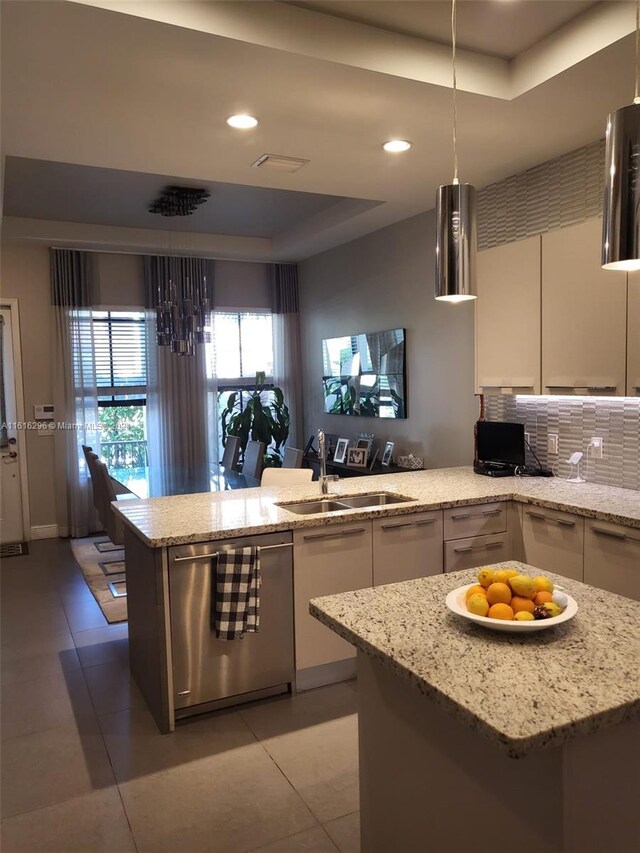 kitchen with a raised ceiling, light stone countertops, sink, and stainless steel dishwasher