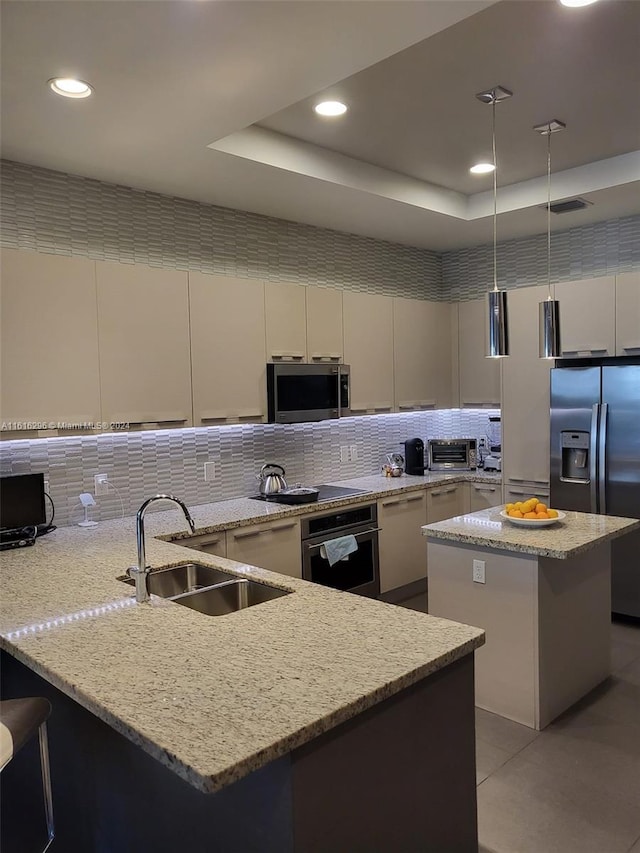 kitchen with decorative backsplash, a raised ceiling, appliances with stainless steel finishes, a peninsula, and a sink