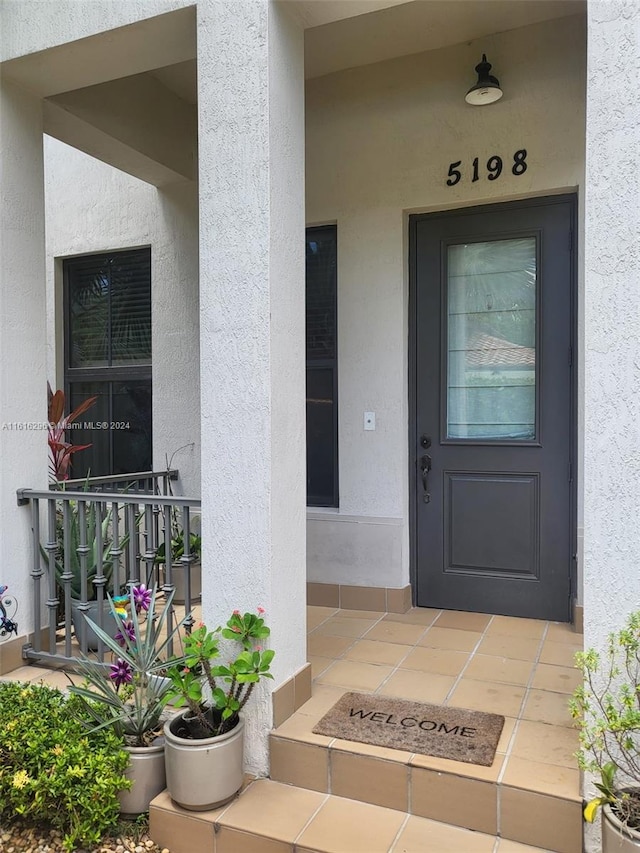 doorway to property featuring covered porch and stucco siding