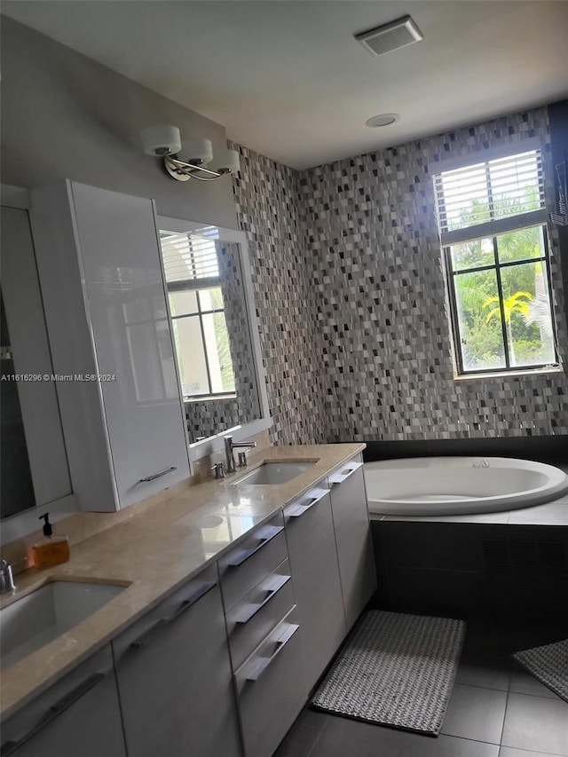 bathroom featuring a relaxing tiled tub, double vanity, tile walls, and tile patterned floors