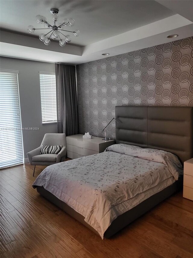 bedroom with wood-type flooring and a tray ceiling