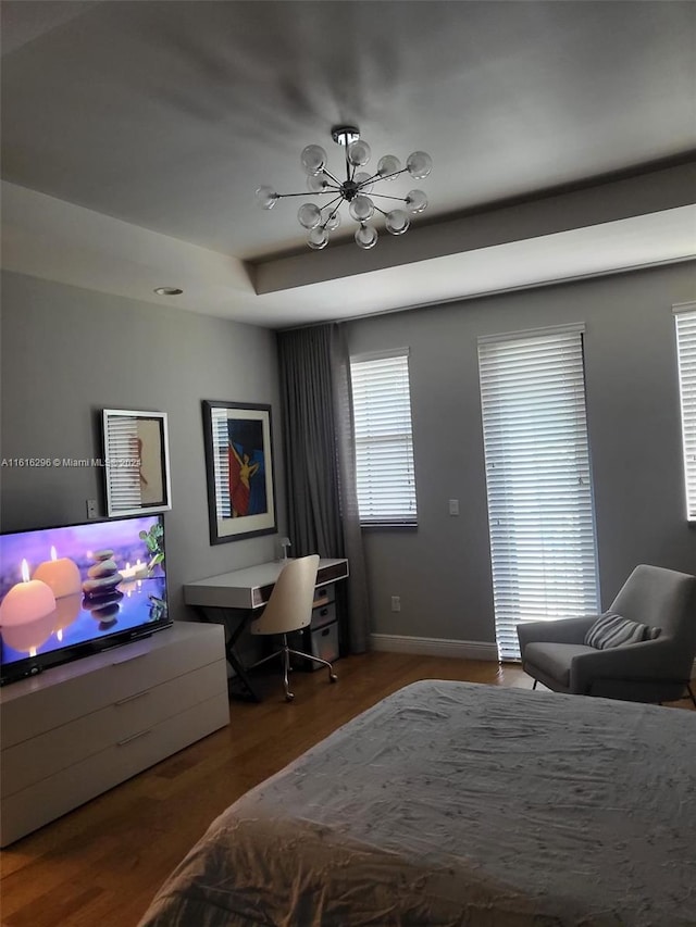 bedroom featuring an inviting chandelier, wood-type flooring, and a tray ceiling