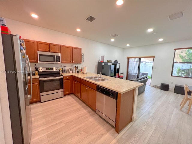 kitchen featuring kitchen peninsula, appliances with stainless steel finishes, and light wood-type flooring