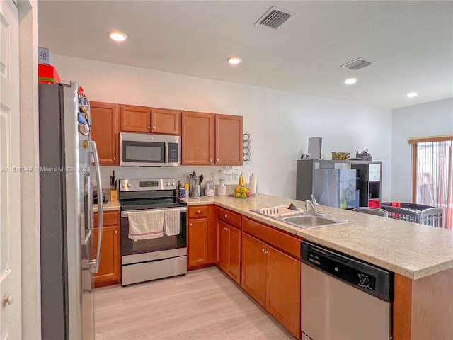 kitchen with kitchen peninsula, stainless steel appliances, light hardwood / wood-style floors, and sink