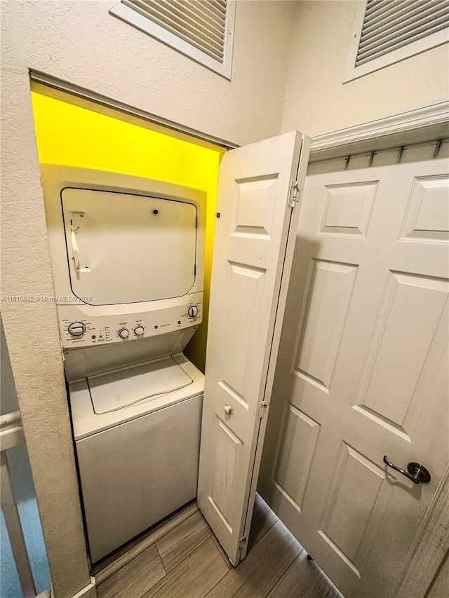 washroom featuring dark wood-type flooring and stacked washer and clothes dryer