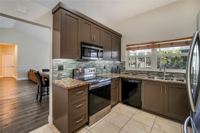 kitchen featuring lofted ceiling, light hardwood / wood-style flooring, stainless steel appliances, stone counters, and sink