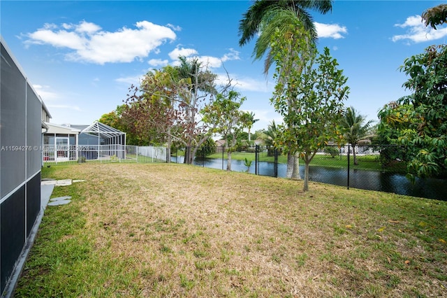 view of yard featuring a water view and glass enclosure