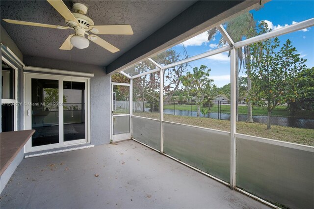 unfurnished sunroom with a water view and ceiling fan