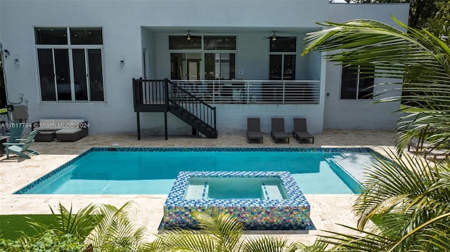 view of swimming pool with ceiling fan, a patio area, and an in ground hot tub