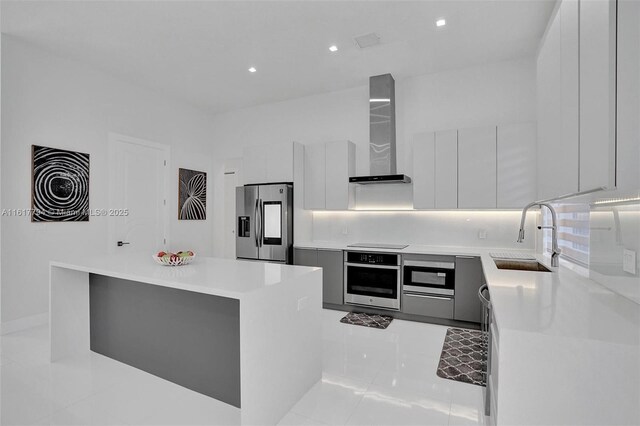 kitchen with appliances with stainless steel finishes, wall chimney exhaust hood, sink, backsplash, and a kitchen island