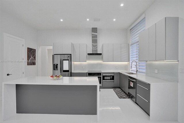 kitchen with black appliances, a center island, gray cabinetry, wall chimney range hood, and sink