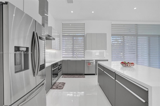 kitchen with decorative backsplash, light tile patterned floors, appliances with stainless steel finishes, and gray cabinets