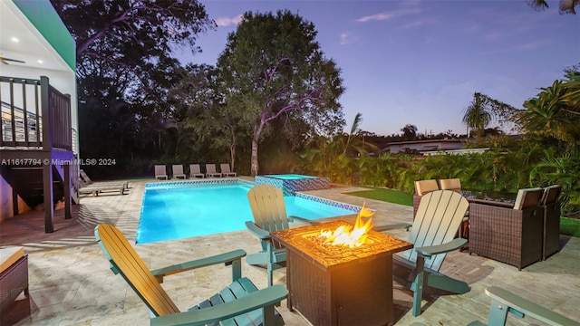 pool at dusk with a fire pit, an in ground hot tub, and a patio area