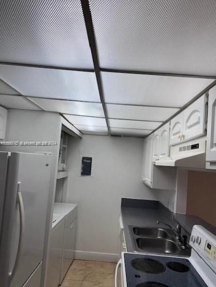 kitchen with light tile patterned flooring, white cabinetry, a paneled ceiling, stainless steel fridge, and sink