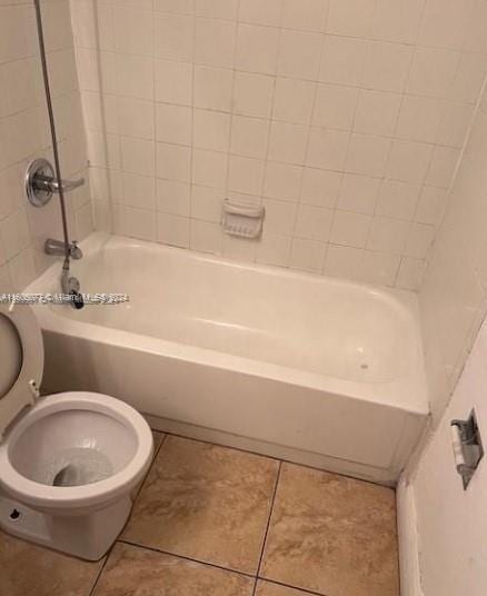 bathroom featuring toilet, tiled shower / bath, and tile patterned flooring