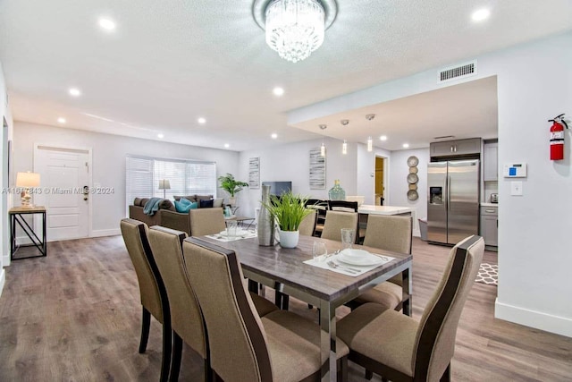 dining room with a textured ceiling, hardwood / wood-style floors, and an inviting chandelier