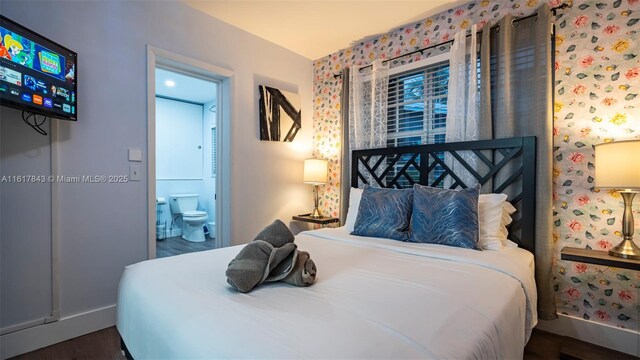 bedroom with ensuite bath and dark hardwood / wood-style flooring