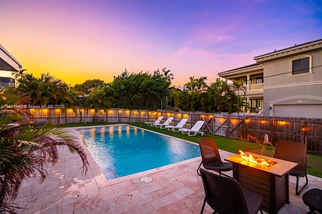 pool at dusk featuring a patio area and a fire pit