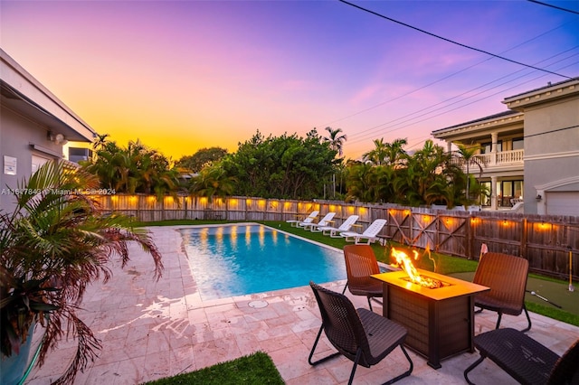 pool at dusk with a patio area and an outdoor fire pit