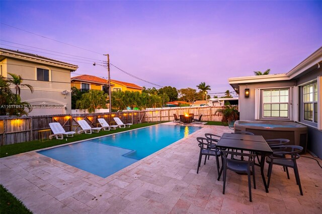 pool at dusk featuring a patio and a jacuzzi