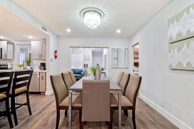 dining area featuring an inviting chandelier, a textured ceiling, and light wood-type flooring