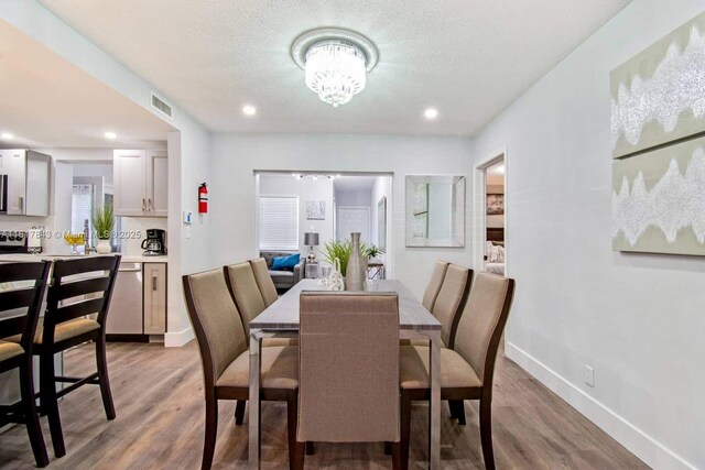 dining space with an inviting chandelier, light hardwood / wood-style flooring, and a textured ceiling