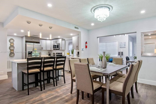 dining space with a textured ceiling, dark hardwood / wood-style flooring, and a notable chandelier