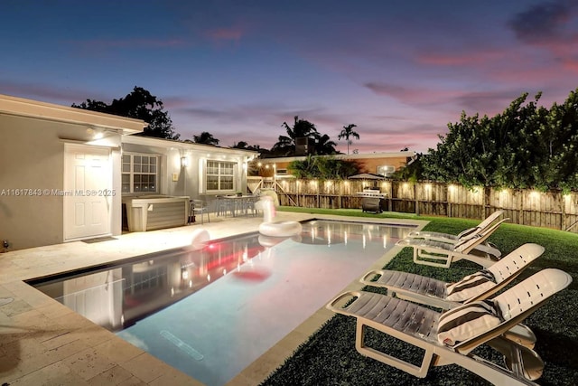 pool at dusk featuring a patio