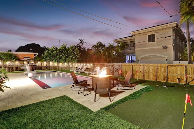 pool at dusk featuring a fire pit, a patio, and a yard