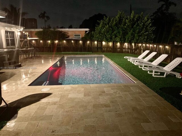 pool at twilight with a patio area