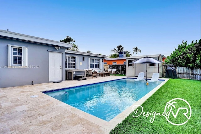 view of swimming pool featuring a shed, a lawn, and a patio area