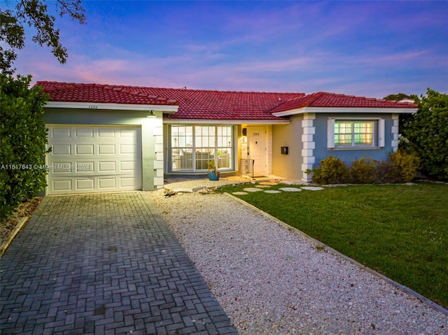 ranch-style house with a garage and a lawn