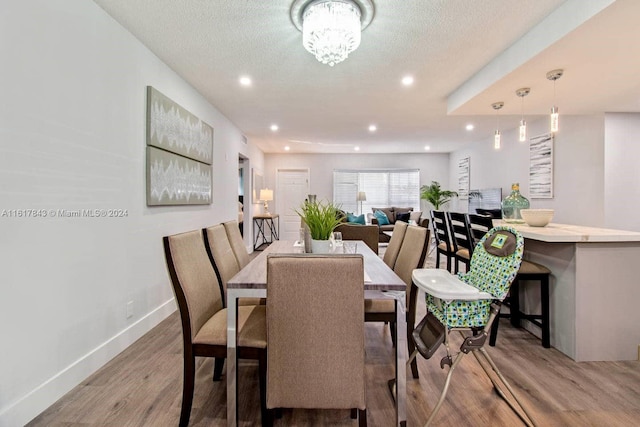 dining room featuring an inviting chandelier, light hardwood / wood-style flooring, and a textured ceiling