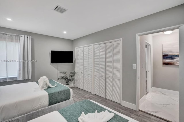 bedroom with wood-type flooring and two closets